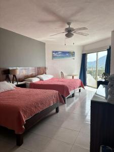 een slaapkamer met 2 bedden en een plafondventilator bij ENNA INN IXTAPA HABITACIóN VISTA AL MAR in Ixtapa