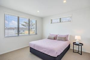 a white bedroom with a bed and two windows at White Beauty in Auckland