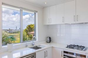 a kitchen with white cabinets and a large window at White Beauty in Auckland