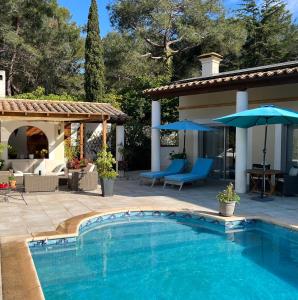 a swimming pool next to a patio with umbrellas at VILLA NATURISTE JO&SPA ANNA'BELLA Luxury Suites "naturist couples only" in Cap d'Agde