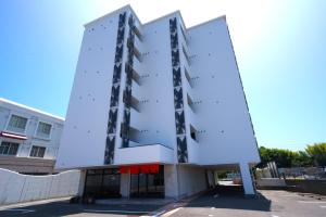 松山的住宿－Hotel Taiyo Nouen Furumitsu，一座高大的白色建筑,有红色遮阳篷