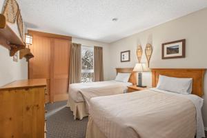 a hotel room with two beds and a window at Tantalus Resort Lodge in Whistler