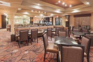 un restaurante con mesas y sillas y un bar en Holiday Inn Hotel & Suites Tulsa South, an IHG Hotel, en Tulsa