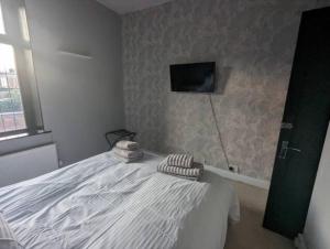 1 dormitorio con 1 cama y TV en la pared en 2 BDR House - Ideal for Short Breaks & Contractors, en Rochdale