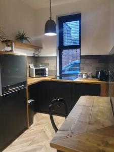 a kitchen with a table and a counter with a microwave at 2 BDR House - Ideal for Short Breaks & Contractors in Rochdale