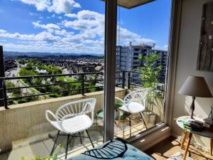 a balcony with white chairs and a view of a city at Hermoso y soleado departamento a pasos de casino Marina del Sol in Talcahuano