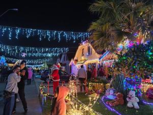 eine Gruppe von Menschen, die vor einem Haus mit Weihnachtslichtern stehen in der Unterkunft Hermoso y soleado departamento a pasos de casino Marina del Sol in Talcahuano