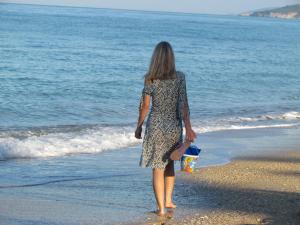 a woman walking on the beach near the water at Hotel Loukas Vrachos in Paralia Vrachou