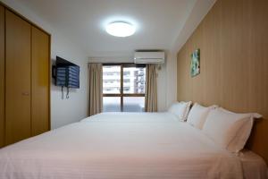 - une chambre avec un grand lit blanc et une fenêtre dans l'établissement TuTuLu302, à Osaka