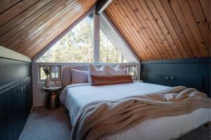 1 dormitorio con 1 cama grande y techo de madera en Mid-Century Cabin Perfect for Romantic Getaway, en Running Springs