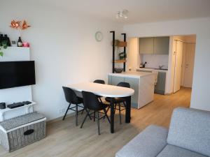 ein Wohnzimmer mit einem Tisch und Stühlen sowie eine Küche in der Unterkunft Riva Bella 102 right on the beach in Nieuwpoort
