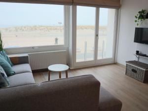 een woonkamer met een bank en een groot raam bij Riva Bella 102 right on the beach in Nieuwpoort