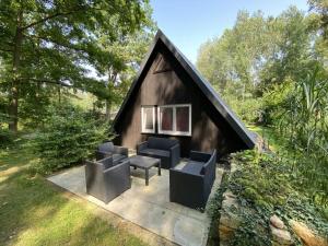 una pequeña casa con techo negro con sofás y sillas en Holiday home Seehütte, en Kleinsaubernitz