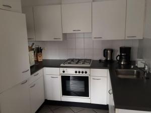 una cucina con mobili bianchi, fornelli e lavello di Holiday home Watersnip 5 a Lemmer Altre 17 foto