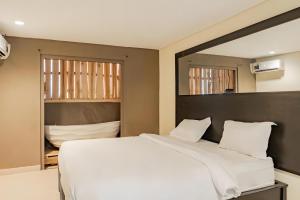 a bedroom with a large white bed and a mirror at Super OYO Airport Kuta Bali Hotel in Kuta