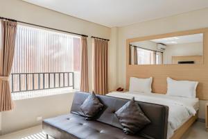 1 dormitorio con cama, sofá y ventana en Super OYO 93765 Airport Kuta Bali Hotel en Kuta