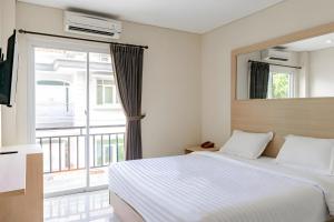 Un pat sau paturi într-o cameră la Super OYO 93765 Airport Kuta Bali Hotel