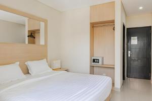 1 dormitorio con cama blanca y espejo en Super OYO 93765 Airport Kuta Bali Hotel en Kuta