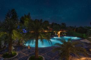 - une vue nocturne sur une piscine bordée de palmiers dans l'établissement Resort De Coracao - Corbett , Uttarakhand, à Rāmnagar