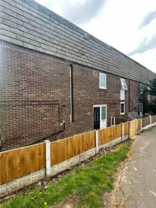a brick building with a fence in front of it at Completely Renovated House with 4 Double Beds in Halton