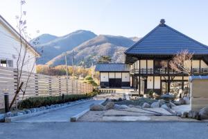 un edificio con techo negro con montañas al fondo en 藤左ヱ門の宿, en Sudagai