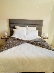 a bed with a black and white comforter and two tables at Lagoon Staycation in Walvis Bay