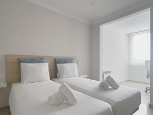 Majordoms - Ca les Cosines 48 في بانيوليس: سريرين في غرفة بيضاء عليها مناشف