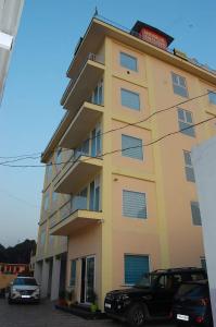 Hotel Shiwalik Enclave في Baddi: مبنى اصفر فيه سيارات تقف امامه