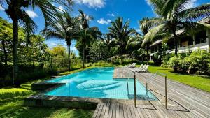 a swimming pool in a backyard with palm trees at Appartement 2 Chambres Grande Piscine et Proche de la Plage in Tamarin