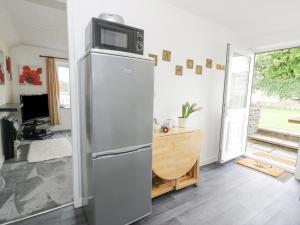 a kitchen with a refrigerator with a microwave on top at Halcyon Annexe in Moelfre