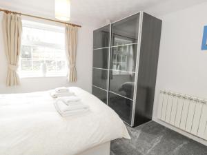 una camera con letto bianco e armadio in vetro di Halcyon Annexe a Moelfre