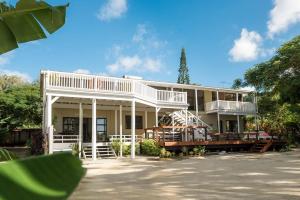 a large white house with a porch and balcony at B's Beach House on Muri Lagoon in Rarotonga