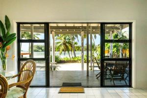 uma sala de jantar com portas de vidro deslizantes e uma mesa em B's Beach House on Muri Lagoon em Rarotonga