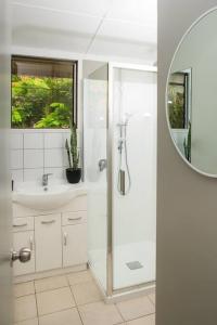 a white bathroom with a shower and a sink at B's Beach House on Muri Lagoon in Rarotonga
