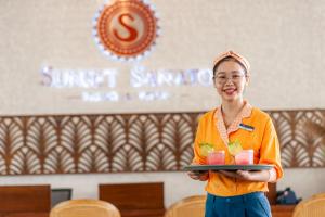 une femme tient un plateau de nourriture dans l'établissement Sunset Sanato Resort & Villas, à Duong Dong