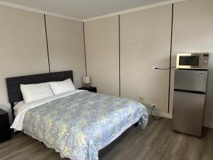 a bedroom with a bed with a microwave and a refrigerator at City Centre Motel II in Hope