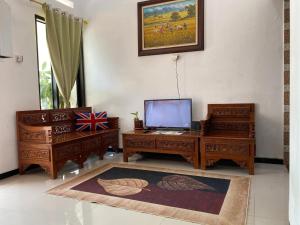 sala de estar con 2 muebles de madera y TV en Villa Murah Malang en Malang