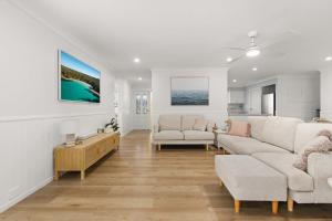 a living room with two white couches and a table at The 19th Hole by Experience Jervis Bay in Sanctuary Point