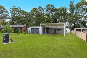 una casa con un césped verde delante de ella en The 19th Hole by Experience Jervis Bay, en Sanctuary Point