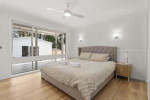 a bedroom with a bed and a large window at The 19th Hole by Experience Jervis Bay in Sanctuary Point