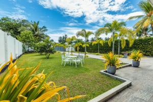 un jardín con mesas, sillas y palmeras en The Palace by Ocean, en Bentota