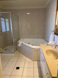 a bathroom with a tub and a shower and a sink at The Astra Broken Hill in Broken Hill