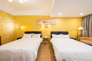 two beds in a room with yellow walls at 一抹云栖世博店-公寓民宿 in Shanghai