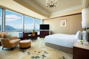 a hotel room with a bed and a desk and a large window at Shangri-La Wenzhou in Wenzhou