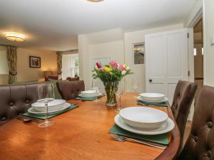 une salle à manger dotée d'une table avec des assiettes et des fleurs dans l'établissement North Mains Cottage - Craigievar Castle, à Alford