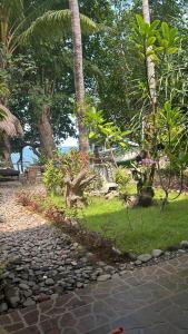 a stone walkway next to a beach with palm trees at Homestay on the beach in Tejakula