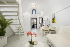 ein weißes Wohnzimmer mit einer Treppe und einem Tisch mit Blumen in der Unterkunft Marillia's elegance residence in Mesariá