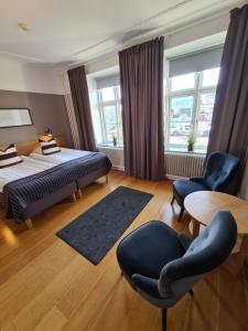 a bedroom with a bed and two chairs and a table at Hamnhotellet Kronan in Landskrona