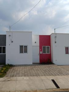 un edificio blanco y rojo con una puerta roja en MINI CASA ECOTERRA SANTA ANA en Santa Ana