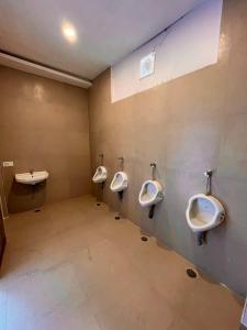 baño con 3 urinarios y lavamanos en VISTA HOSTEL Near Mall Road Manali - with Playing Zone & Gym en Manāli